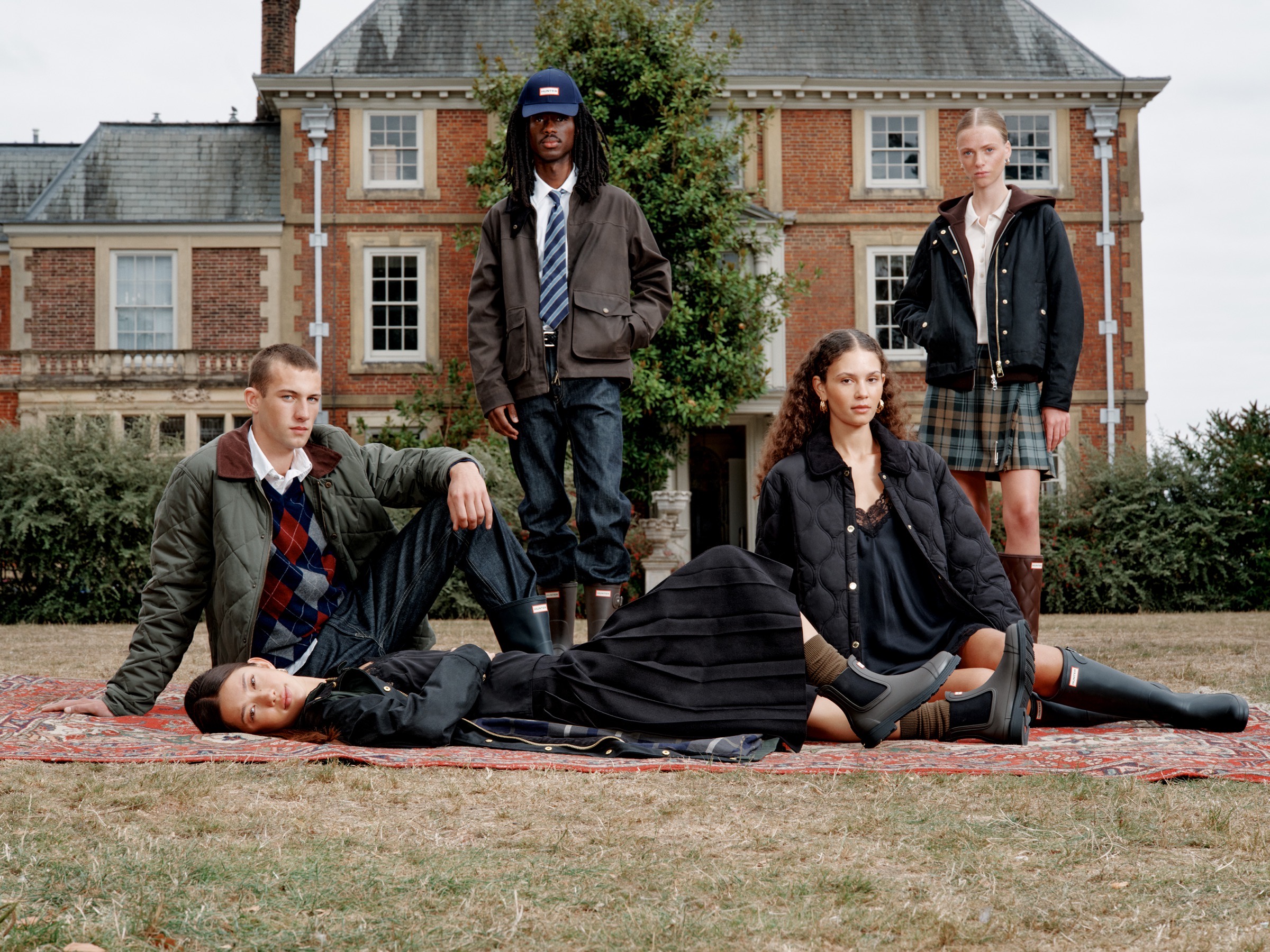 Five models in Hunter boots and tartan on the lawn of an English country house